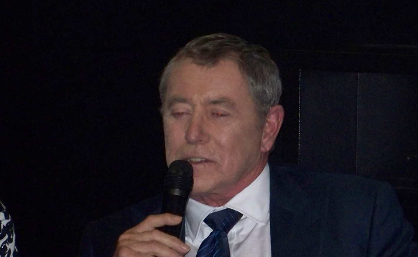 John Nettles auf der Bühne mit einem Mikrofon in der Hand.